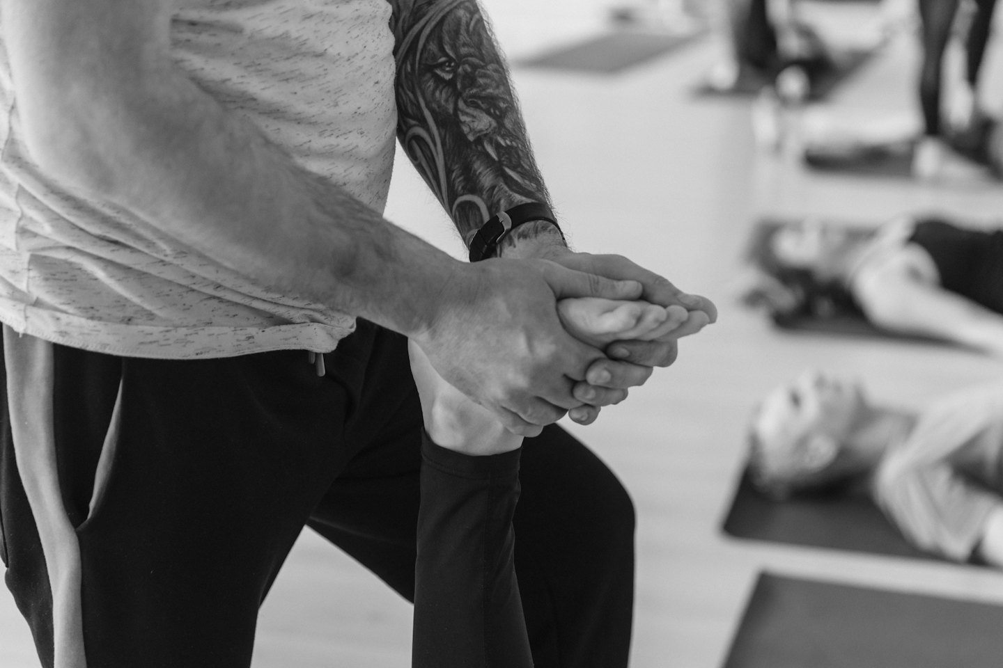 Mani tatuate aiutano un piede in una lezione di yoga.